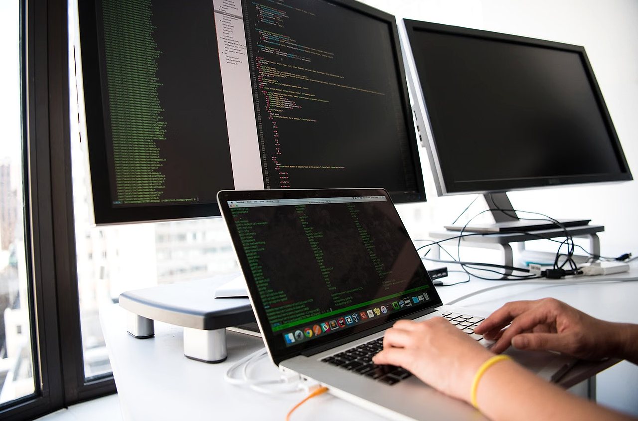 Person typing on laptop with code screens